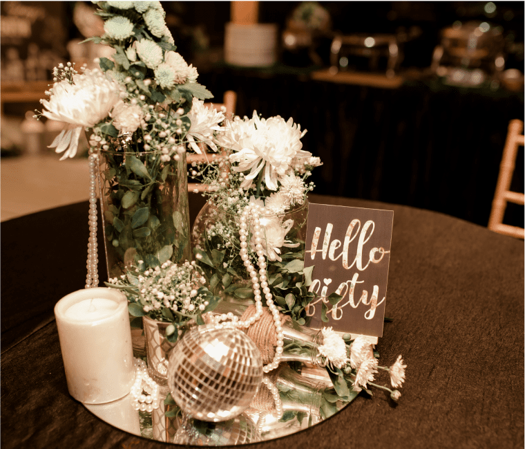 Table centerpiece with flowers and decorative items.